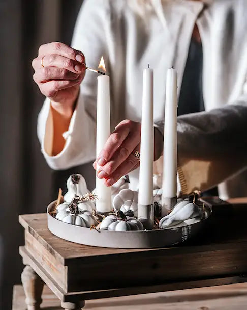 Närbild av händer som tänder ljus i en vit adventsljusstake med metalldetaljer | A Lot Decoration | Lilla Hem