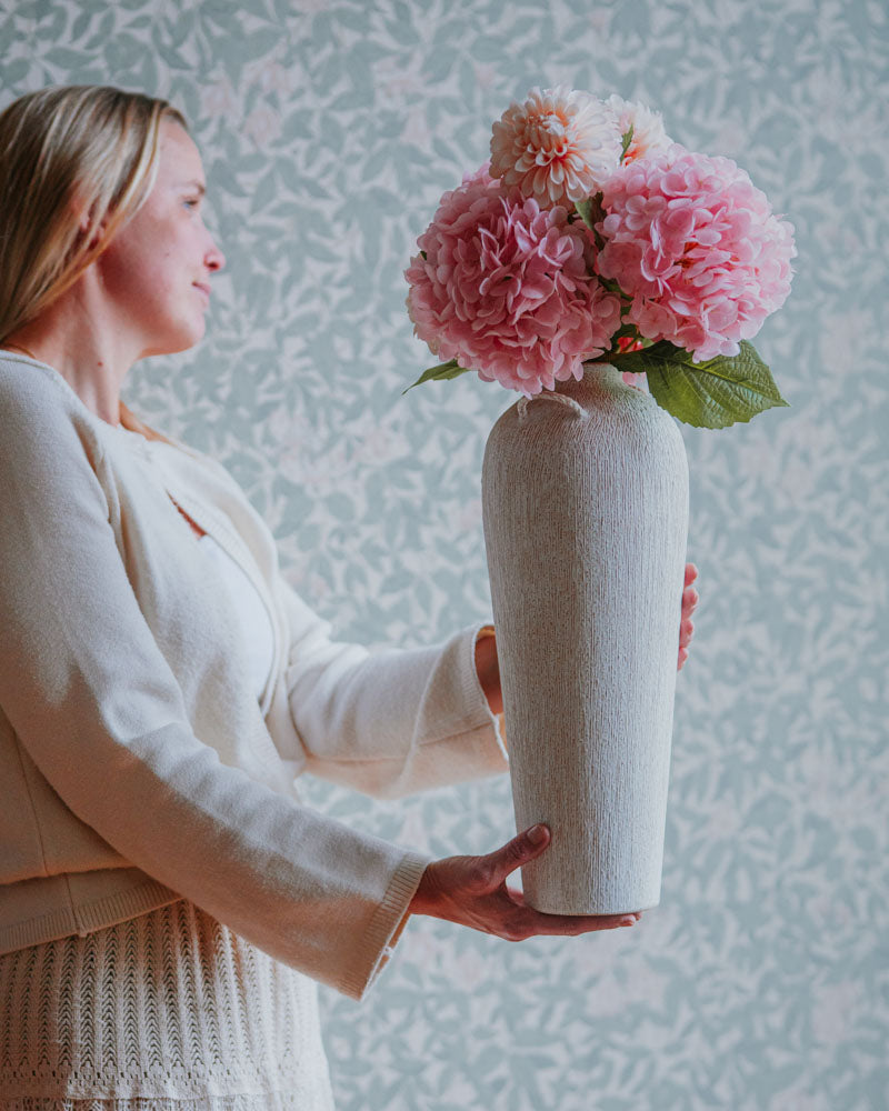 Modell håller en grå vas med rosa pioner, sedd från sidan | A Lot Decoration | Lilla Hem