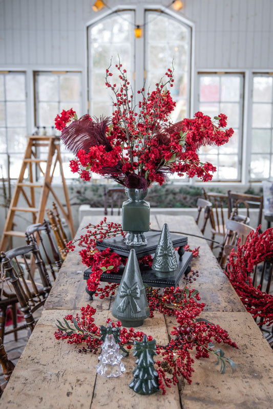 Röd bärkrans arrangerad på träbord tillsammans med dekorativa granfigurer och blomsterarrangemang | A Lot Decoration | Lilla Hem