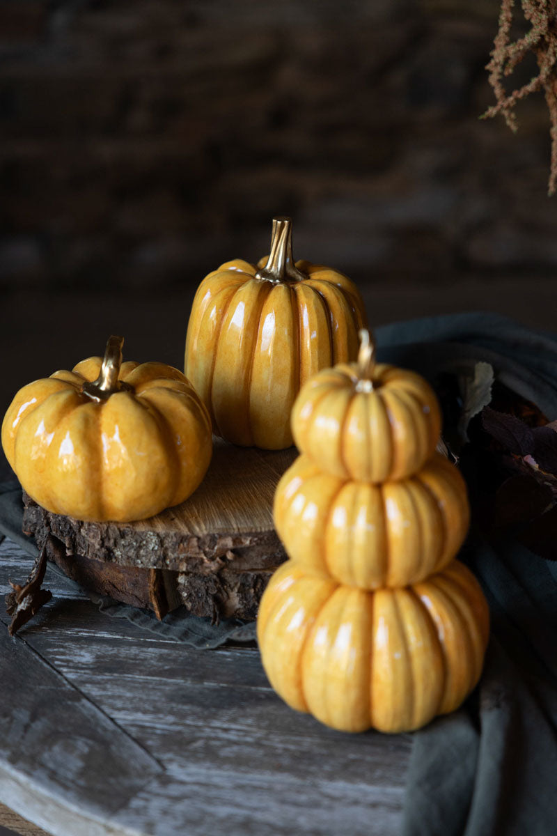 Tre gyllene pumpor med glansig finish arrangerade på trä mot mörk bakgrund | A Lot Decoration | Lilla Hem