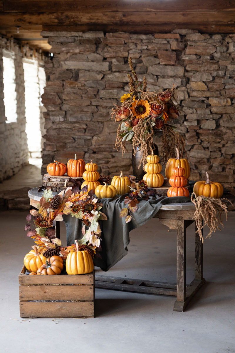 Dekorativa gula pumpor arrangerade på träbord med höstblommor och torkad vegetation mot tegelvägg | A Lot Decoration | Lilla Hem