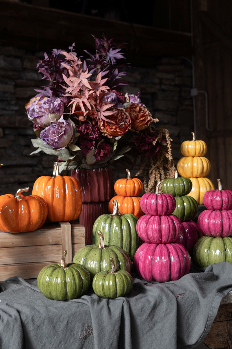 Dekorativ pumpor i orange, rosa och grön färg arrangerade på grått tyg med höstblommor i bakgrunden | A Lot Decoration | Lilla Hem