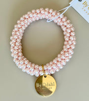 Armband med rosa pärlor i elastisk snodd och guldpläterad bricka, framifrån | By Odahl Sweden | Lilla Hem