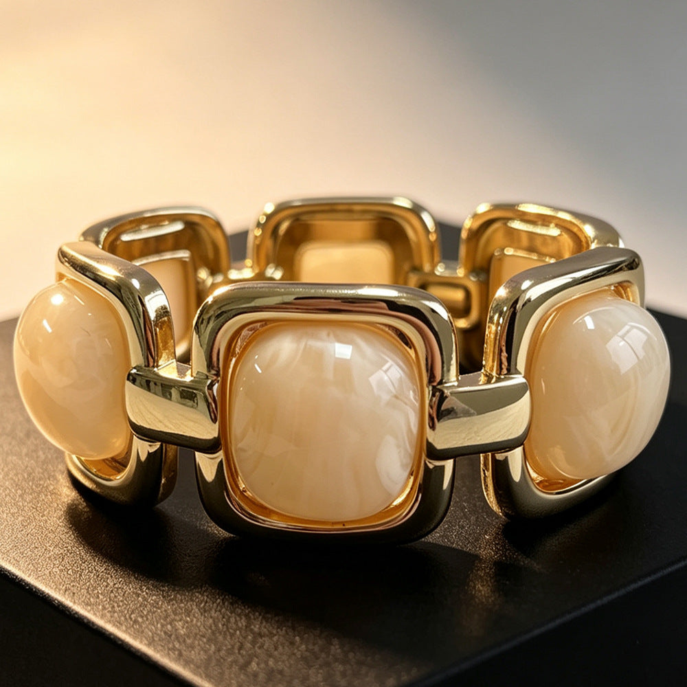 Armband med beige acetatstenar i guldmetall, fotograferat framifrån på svart underlag | By Odahl Sweden | Lilla Hem