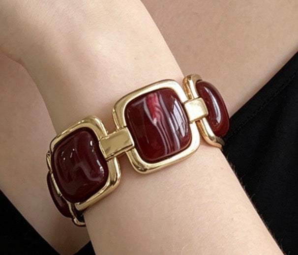 Armband med vinröda acetatstenar i guldiga kvadratiska fästen, bärat på handled | By Odahl Sweden | Lilla Hem