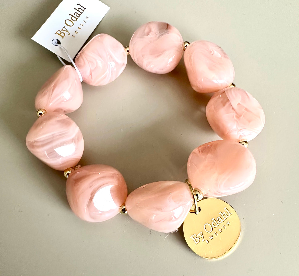 Armband med ljusrosa marmorerade pärlor och guldiga detaljer, fotograferat ovanifrån mot neutral bakgrund | By Odahl Sweden | Lilla Hem