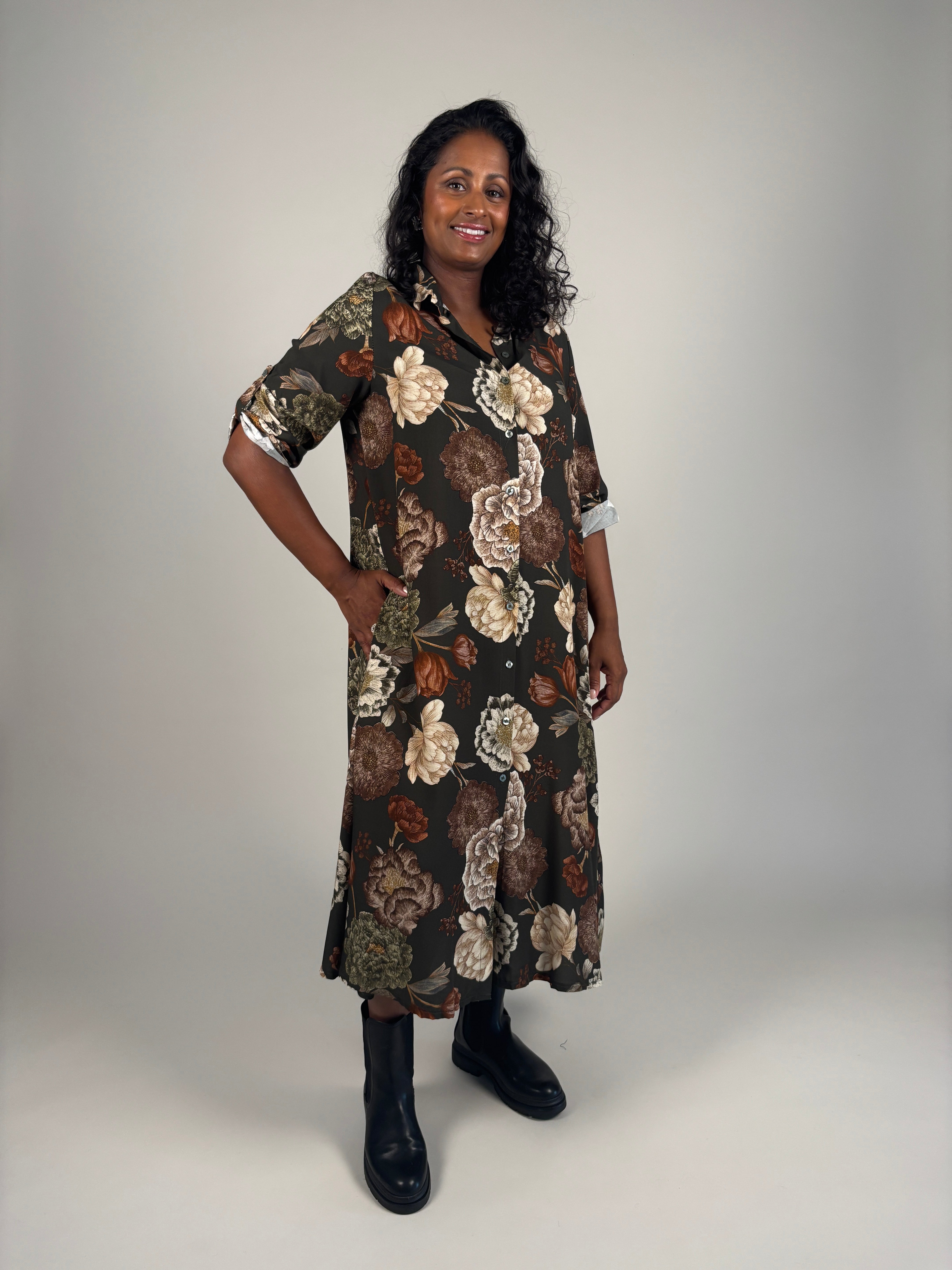 Modell bär skjortklänningen framifrån med stort blommigt tryck i beige och rostfärger på svart botten | Camicia | Lilla Hem