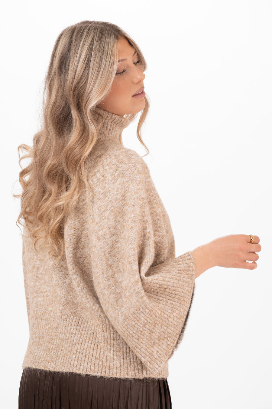 Modell bär beige stickad tröja med veckad ärm, sedd från sidan | Capri Collection | Lilla Hem