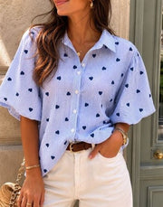 Modell bär ljusblå blus med marinblå hjärtmönster och puffärmar, sett framifrån | Caramelle Fashion | Lilla Hem