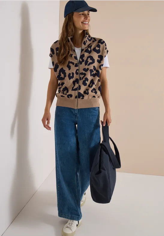 Modell bär leopardmönstrad väst över vit tröja, kombinerat med vida jeans och marinblå keps | Cecil | Lilla Hem