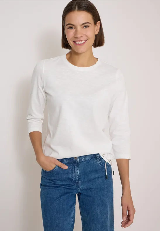 Modell bär vit långärmad t-shirt med rund hals, kombinerad med blå jeans, sett framifrån | Cecil | Lilla Hem