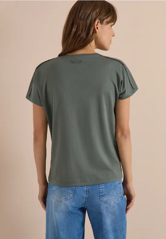 Modell bär grågrön t-shirt sett bakifrån tillsammans med blå jeans | Cecil | Lilla Hem