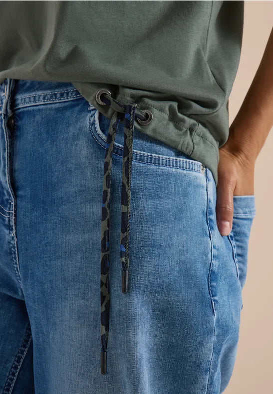 Närbild på jeansbyxor med grå tröja, fokus på dragsko i midjan | Cecil | Lilla Hem