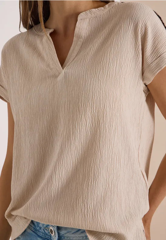 Modell bär beige blusen framifrån med V-ringning och strukturerad vävning | Cecil | Lilla Hem