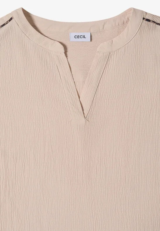 Närbild av beige blus med V-ringning och strukturerad textil, sedd framifrån | Cecil | Lilla Hem