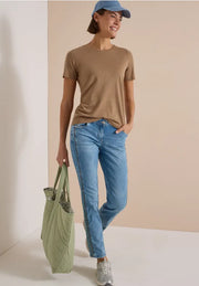 Modell bär beige t-shirt och ljusblå straight jeans, hålls framifrån med grön väska | Cecil | Lilla Hem