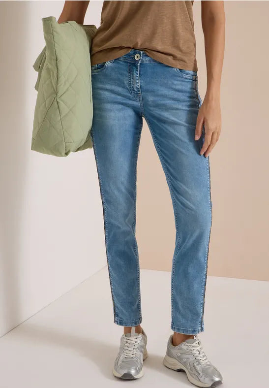 Modell bär ljusblå raka jeans tillsammans med beige tröja och grön jacka | Cecil | Lilla Hem