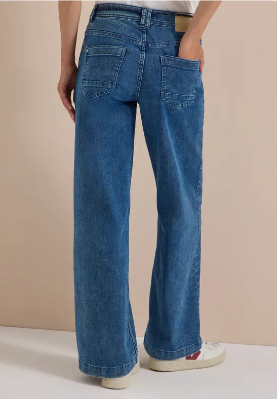 Modell bär blå flare jeans sett bakifrån, visar passformen och bakfickorna | Cecil | Lilla Hem