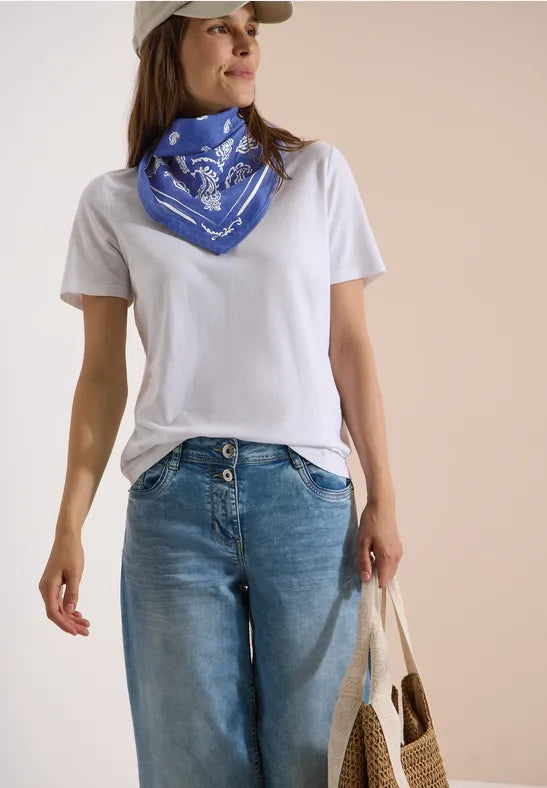Modell bär blå bandana med paisley-mönster runt halsen, kombinerat med vit t-shirt och jeans | Cecil | Lilla Hem