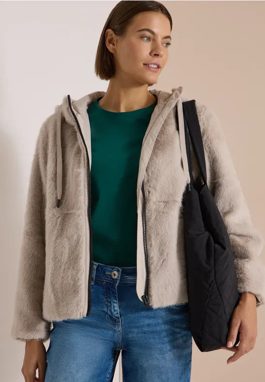 Modell bär beige pälsjacka med huva över grön tröja och jeans, sett framifrån | Cecil | Lilla Hem