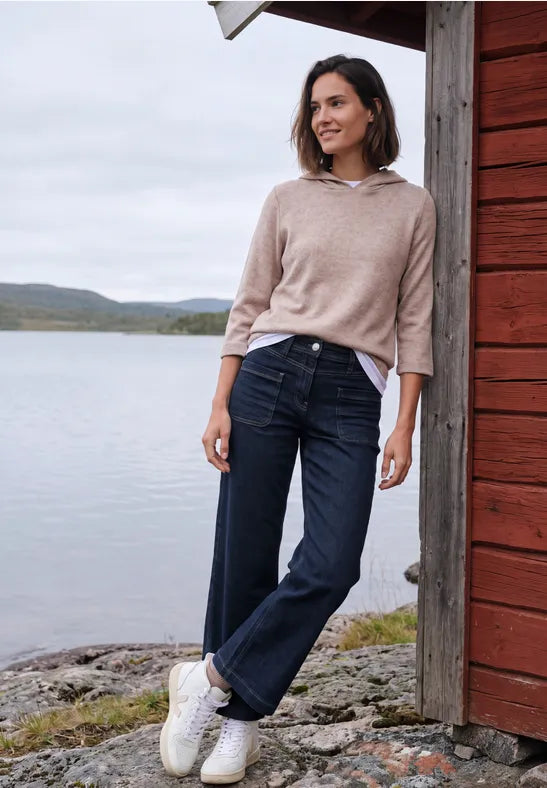 Modell bär mörkblå jeans med patchdetaljer, sett framifrån vid sjöstrand | Cecil | Lilla Hem