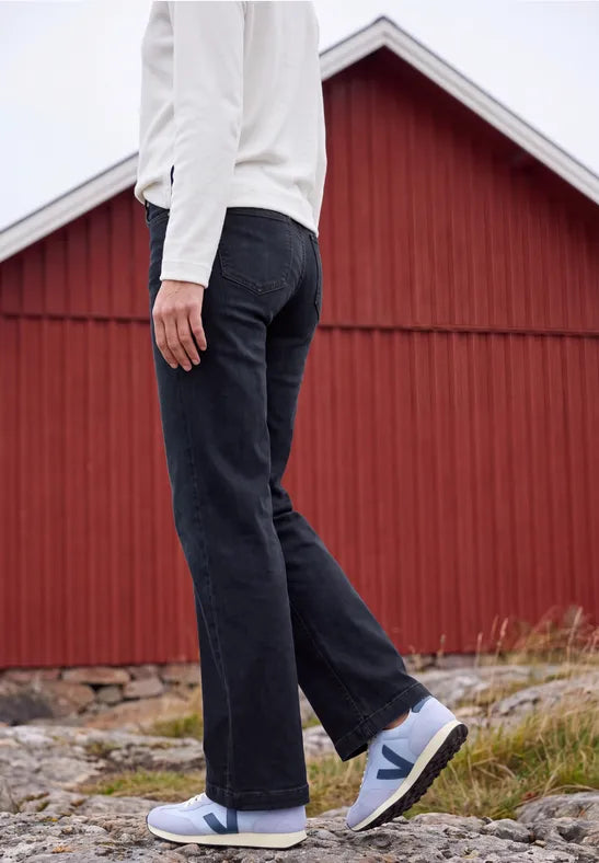 Modell bär mörkblå jeans sett från sidan framför röd ladugård | Cecil | Lilla Hem