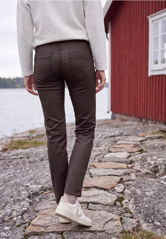 Modell bär bruna coatade jeans sett bakifrån vid stenväggen | Cecil | Lilla Hem