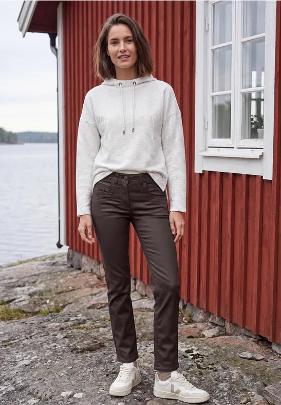 Modell bär beige hoodie och mörkbruna coated jeans, fotograferad framifrån utomhus | Cecil | Lilla Hem