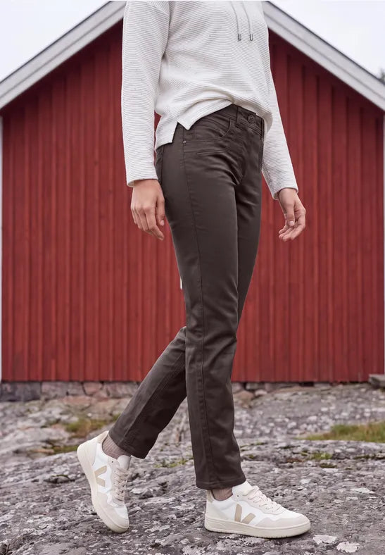 Modell i sidoprofil bär svarta stretchbyxor med vit ribbad tröja och vita sneakers | Cecil | Lilla Hem