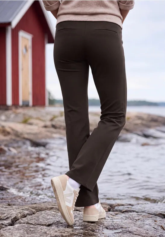Modell bär svarta bootcut-byxor sett bakifrån vid stenig strand | Cecil | Lilla Hem
