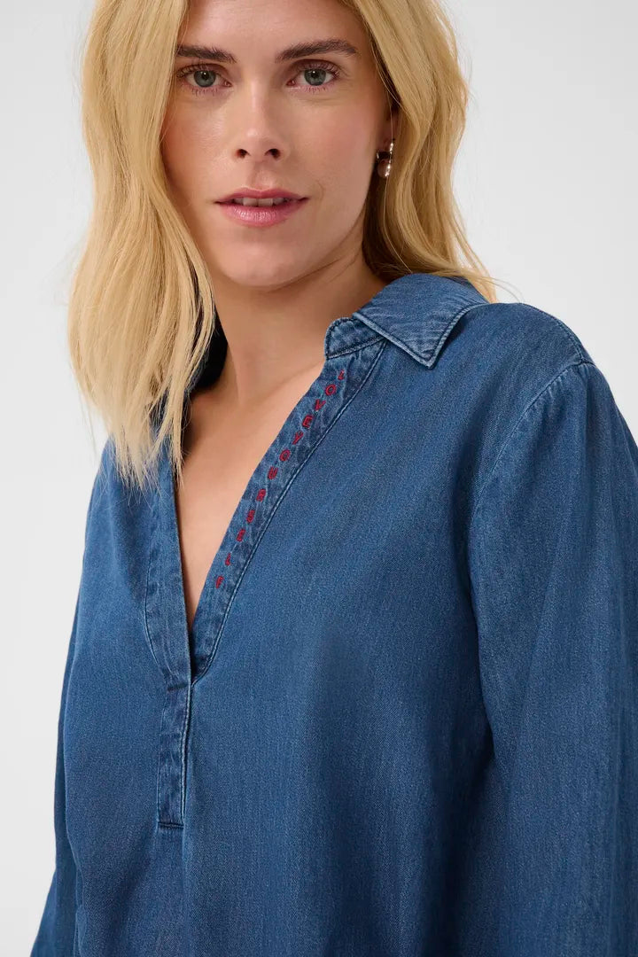 Modell bär denimtunika framifrån med röd broderad detalj längs knäppningen | CULTURE | Lilla Hem
