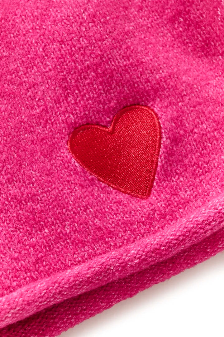 Närbild av rosa mössa med röd hjärtformad applikation och texturerad stickad yta | CULTURE | Lilla Hem