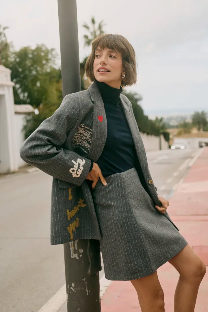 Modell bär grå randig blazer med broderad detalj, kombinerad med svart polotröja, fotograferad utomhus | CULTURE | Lilla Hem