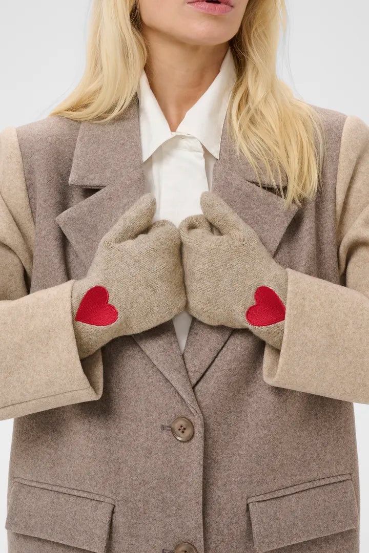 Modell bär beige handskar med röda hjärtdetaljer, visade framifrån tillsammans med beige blazer och vit skjorta | CULTURE | Lilla Hem