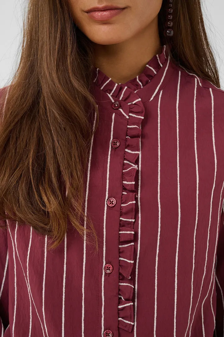 Närbild av burgundy skjorta med vita ränder och volangkant längs knappslitsen | CULTURE | Lilla Hem