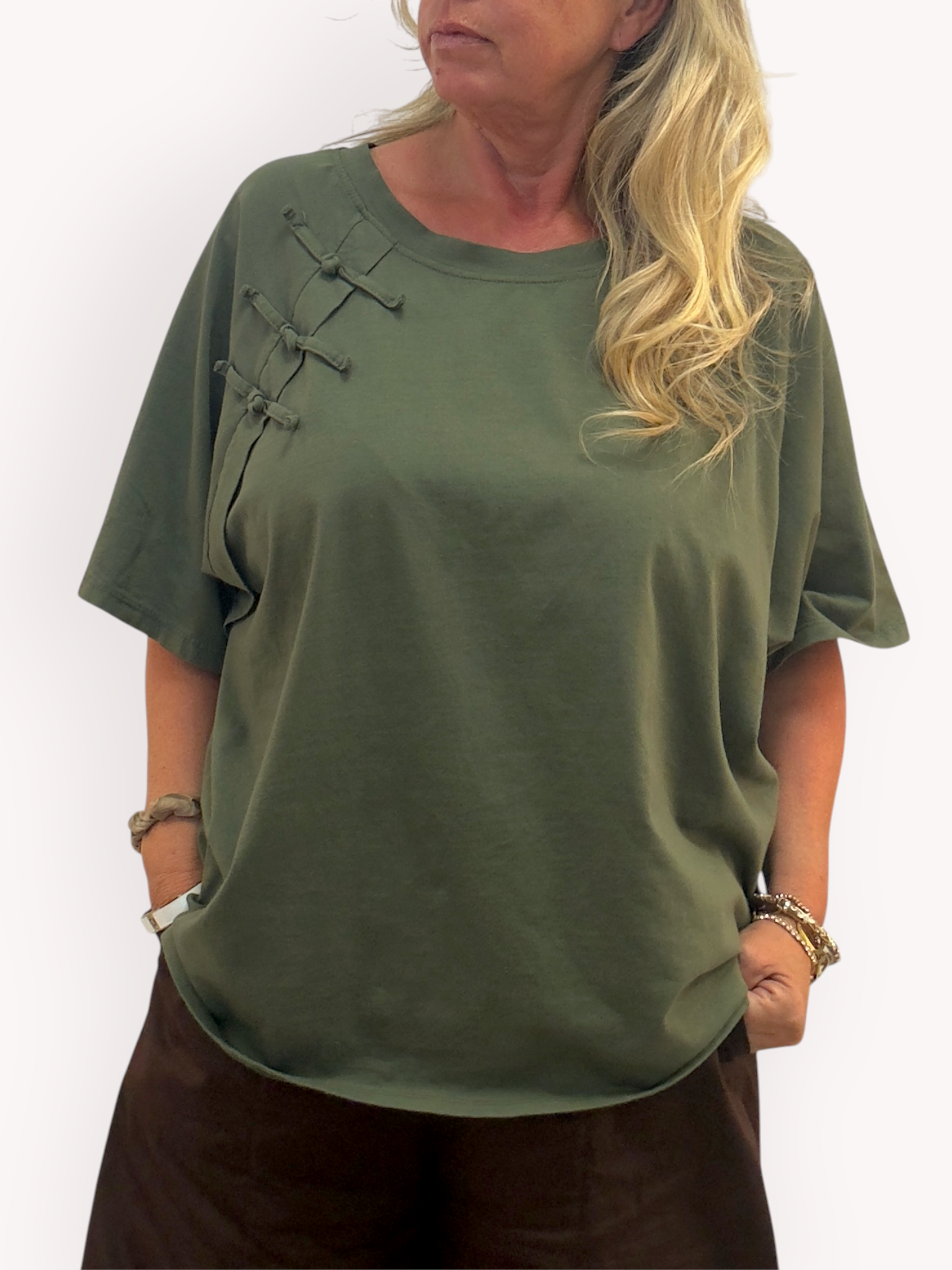 Modell bär olivgrön t-shirt med dekorativa snörknappar på bröstet, sett framifrån | Gemini | Lilla Hem