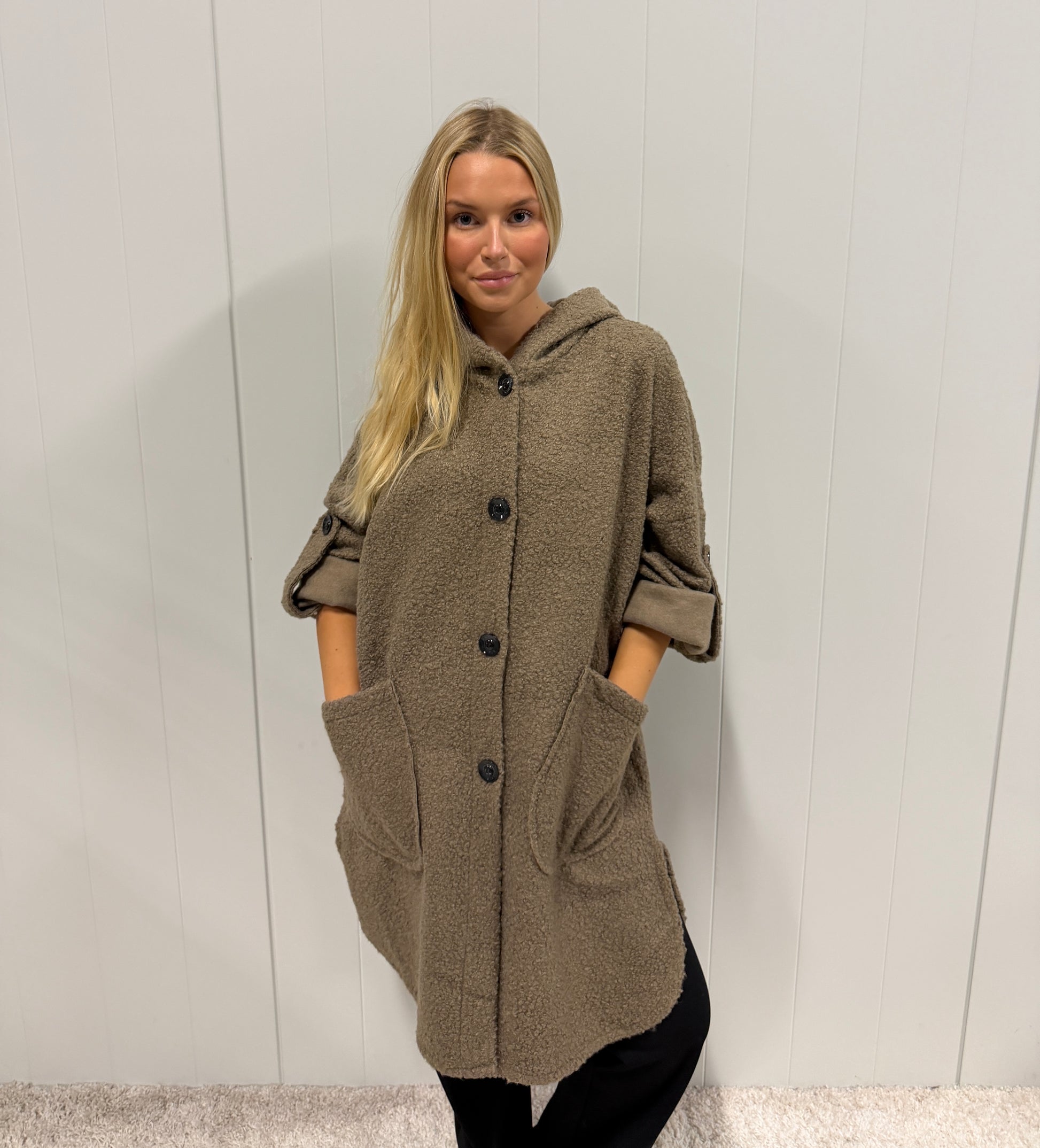Modell bär beige teddykappa med huva och knäppning, sett framifrån mot vit vägg | Jörlevik of Sweden | Lilla Hem