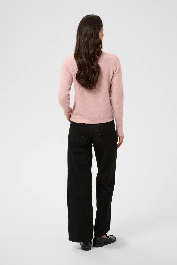 Modell bär rosa stickad kofta och svarta jeans, sett bakifrån mot vit bakgrund | KAFFE | Lilla Hem