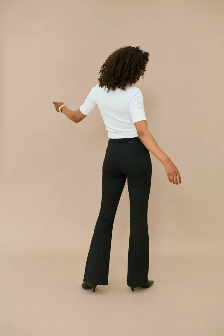 Modell bär vita tröja och svarta utsvängda jeans, sedd bakifrån mot beige bakgrund | KAFFE | Lilla Hem