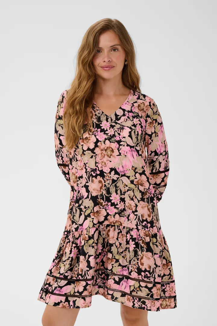 Modell bär blommig klänning med rosa och beiga blommor på svart botten, sedd framifrån | KAFFE | Lilla Hem