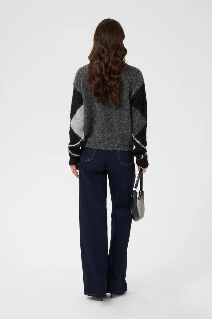 Modell bär cardigan bakifrån med färgblock i grå, svart och vit, kombinerat med mörkblå jeans | KAFFE | Lilla Hem