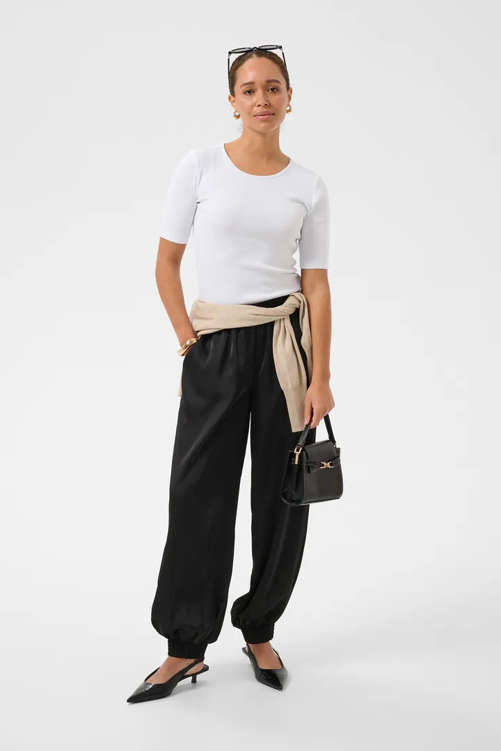 Modell bär vita t-shirt och svarta joggbyxor med beige bälte, sett framifrån | KAFFE | Lilla Hem