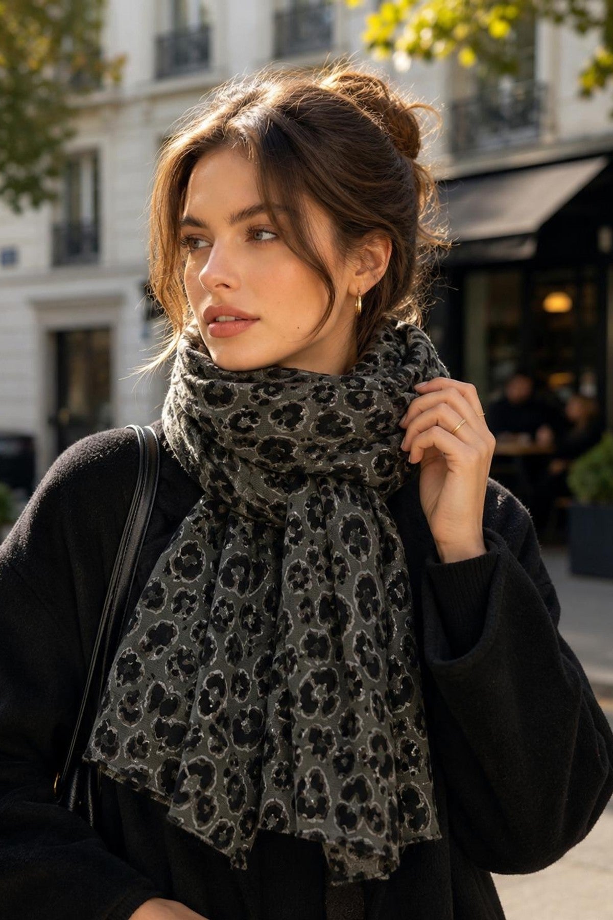 Modell bär leopardmönstrad scarf löst omkring halsen över svart tröja, fotograferad från sidan utomhus | BEST ANGEL | Lilla Hem