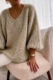 Modell sitter och bär beige stickad oversize-tröja med v-ringning, sedd från överkroppen | RZ FASHION | Lilla Hem