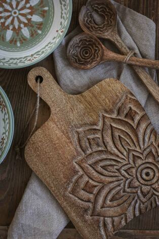 Handkarvad träskärbräda med blomstermotiv, omgiven av dekorativa keramikplattor och linnekudde | Majas Cottage | Lilla Hem