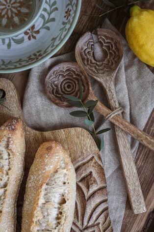 Handkarvade salladsbestick med blomstermotiv ligger på linneduk tillsammans med bröd och citron | Majas Cottage | Lilla Hem