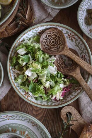 Handkarvade träbestick med blommönster ligger i en skål med grön sallad på trävit bord | Majas Cottage | Lilla Hem