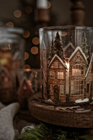 Glaskruka med vinterhus-motiv och snö, tänd ljuslykta framför suddig julbakgrund | Majas Cottage | Lilla Hem