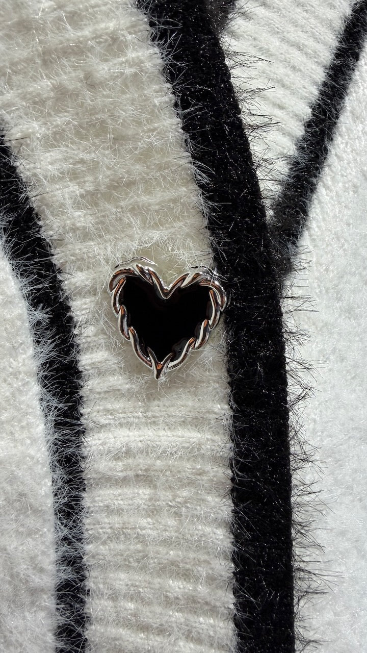 Närbild av cardigan med vertikala svart-vita randiga band och metallhjärtformad knapp i mitten | Caramelle Fashion | Lilla Hem