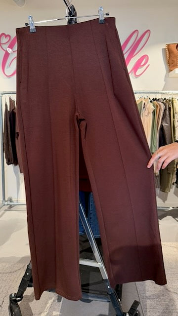 Vinröd byxa hängande på galge, visar pressveck och vid benöppning framifrån | Caramelle Fashion | Lilla Hem